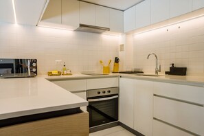 A modern kitchen with white cabinetry, a built-in oven, and a stainless steel range hood. - Large Terrace Studio · Selected Design (H02) (Providencia)