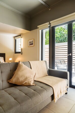 Un salon moderne avec un canapé gris, un plaid beige et un tableau encadré accroché au mur.