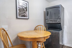 A compact kitchen with a wooden table and chairs, a microwave, and a framed picture on the wall. - The Dapper Duck-Downtown Southern Pines! (Southern Pines)