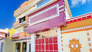 A multi-story building with a prominent red garage door, a sign indicating 'Townhouse' and 'app-serviced,' and a clear blue sky in the background.