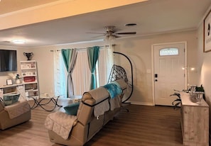 A living room with a sofa, a coffee table, a TV, and a door with a window.
