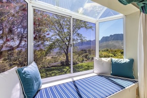 A room with a large window offering a view of a mountainous landscape. - Pure Nature: The Somerset West Wine Region. Ideal for mountain bikers, hikers, and nature lovers (Sir Lowry's Pass)