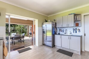 A modern kitchen with white cabinets, a stainless steel refrigerator, and a dining area with a table and chairs. - Pure Nature: The Somerset West Wine Region. Ideal for mountain bikers, hikers, and nature lovers (Sir Lowry's Pass)