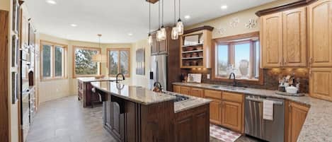A spacious kitchen with a large island, wooden cabinets, and a view of the outdoors.