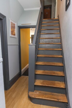 A staircase with wooden steps and a metal handrail, leading to a room with a door. - Cardiff | 4BR | Sleeps 10 | Groups | Contractors (Cardiff)