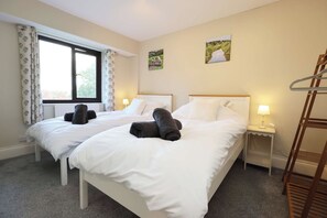 A hotel room with two beds, a window with curtains, a painting on the wall, and a wooden ladder. - Stunning Views | 2-Bed Wye Valley Retreat (Bridstow)