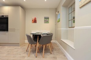 A dining area with a round table, four chairs, and a white radiator. - Ross-on-Wye Stone Cottage | Fishing | Sleeps 4 (Bridstow)