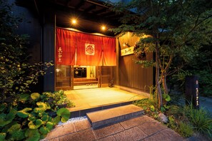 Ein traditionelles japanisches Gebäude mit Holzfassade, einem roten Vorhang und einem Schild mit japanischen Schriftzeichen.