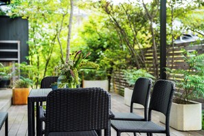 Eine Terrasse mit Korbmöbeln und einem Blumenvasen.