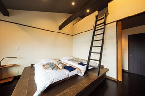 Ein Stockbett mit einer Leiter, ein Schreibtisch mit Lampe sowie eine Tür.