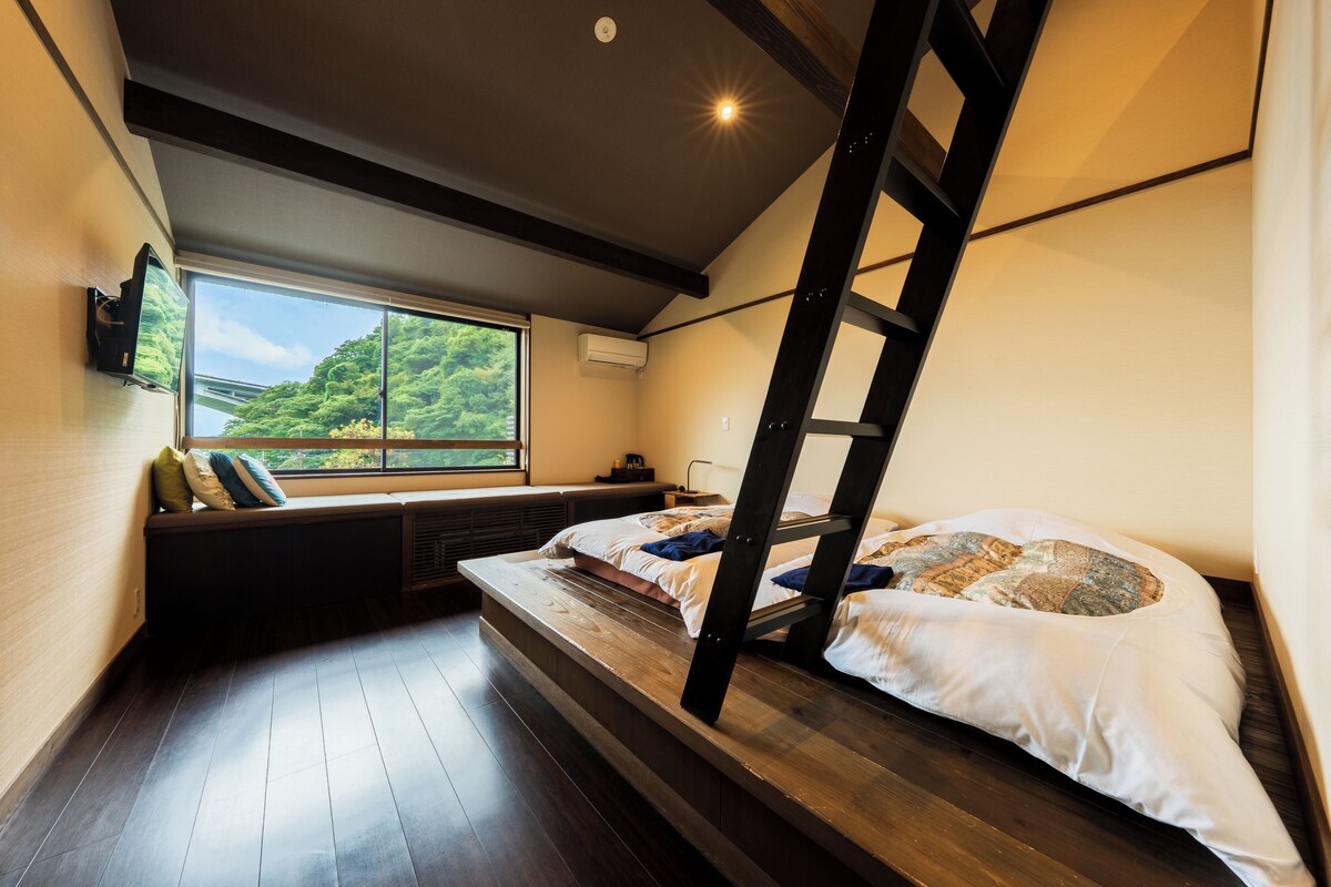 Ein kleines Zimmer mit Etagenbett, Fenster mit Blick auf Grünflächen und festinstalliertem Heizkörper.