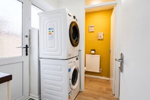 Stacked washer and dryer in the utility area off the hall. - 4-Bed House Sleeps 8 · Free Parking & Patio · 1 Min to Margam Deer Pub (Neath Port Talbot)