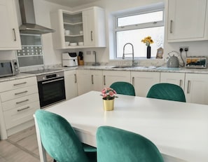 Una cocina moderna con armarios blancos, horno empotrado, microondas y una ventana sobre el fregadero.