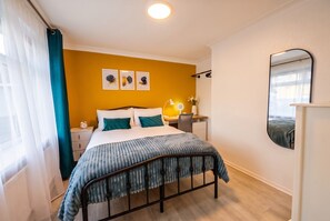 A bedroom with a bed, bedside table, lamp, and a mirror on the wall. - 4-Bed House Sleeps 8 · Free Parking & Patio · 1 Min to Margam Deer Pub (Neath Port Talbot)