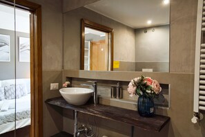 A bathroom with a large mirror, a white sink, and a vase with flowers on the countertop. - Di Martino Residence (Roma)
