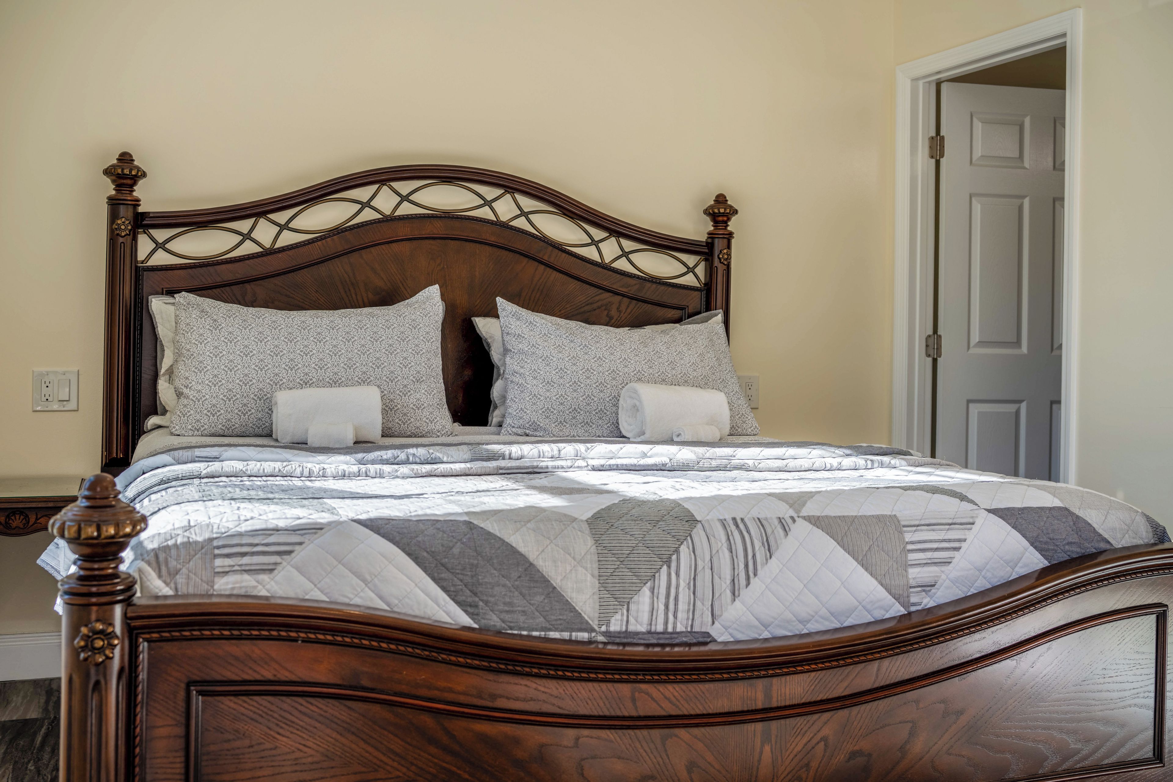 A wooden four-poster bed with a quilted bedspread and multiple pillows.