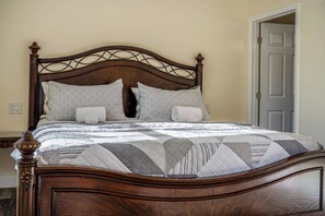 Una cama de madera con dosel y un edredón acolchado, con numerosos cojines.
