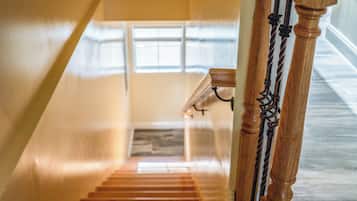 Una escalera de madera con barandilla y un ventanal en la parte superior.
