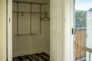 Vestidor con estanterías metálicas, suelo de madera y una puerta que da a un espacio exterior.