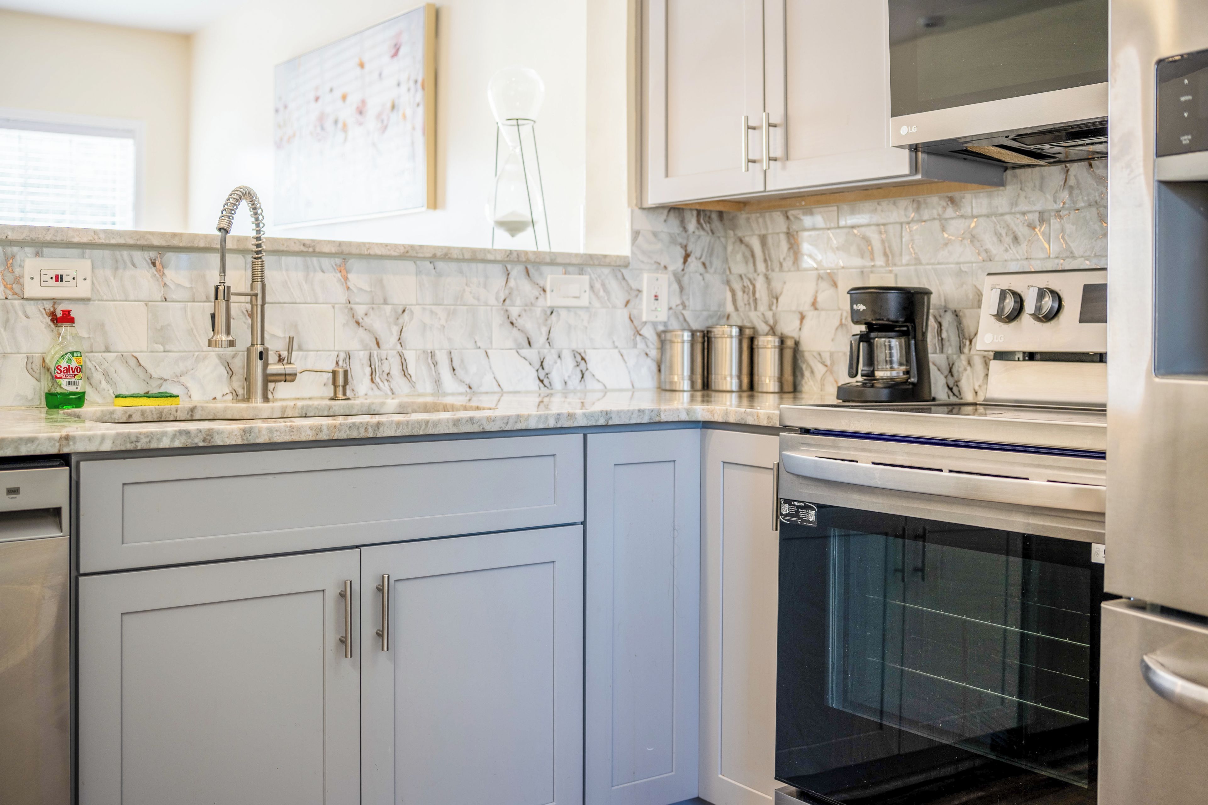 A kitchen with a dishwasher, oven, and a coffee maker.