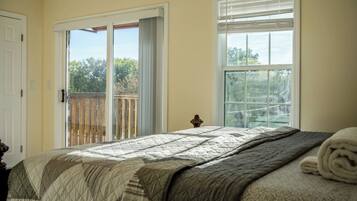 A bedroom with a bed, a door, and a window with blinds.