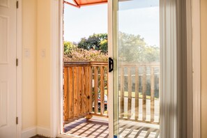 Una puerta corrediza de vidrio que da a una terraza de madera con piso a cuadros.
