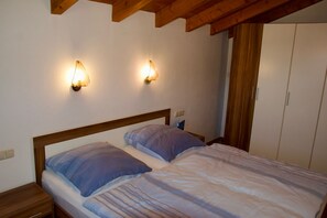 Quarto com cabeceira de madeira, duas mesas de cabeceira, guarda-roupa e luminárias fixadas na parede.