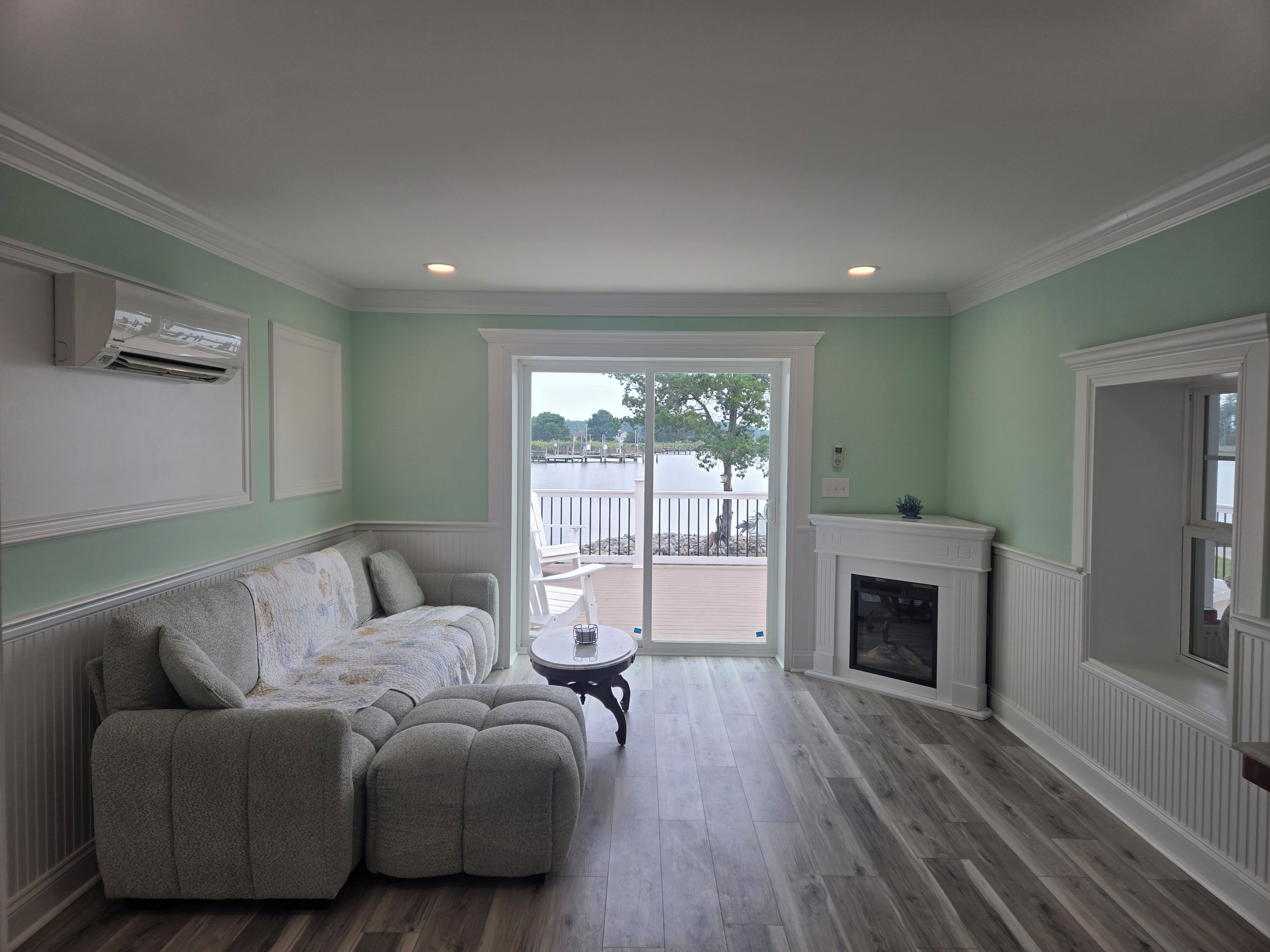 A living room with a sectional sofa, a fireplace, and a view of a dock and water.