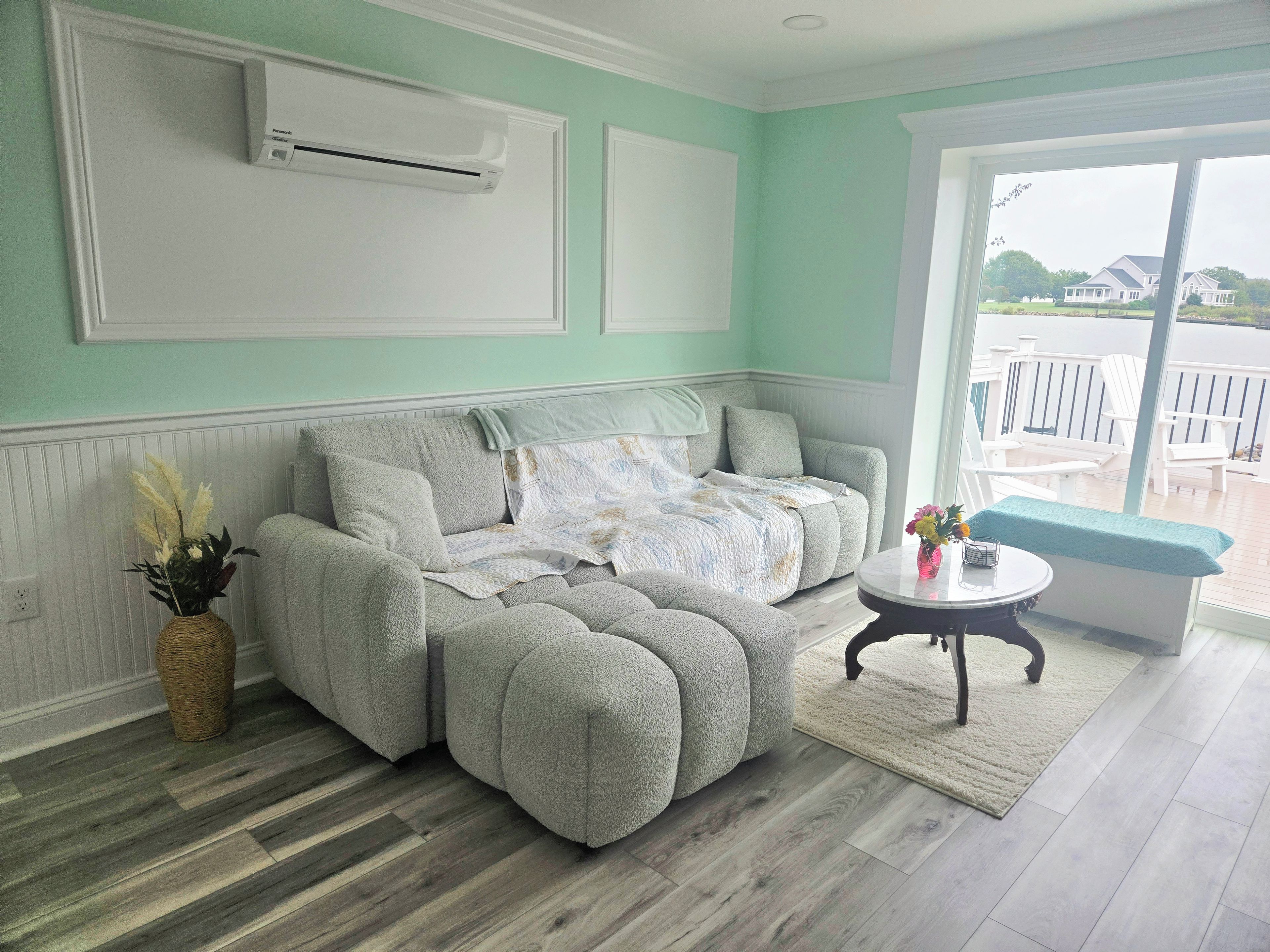 A living room with a sectional sofa, a round coffee table, and a view of a deck through a glass door.