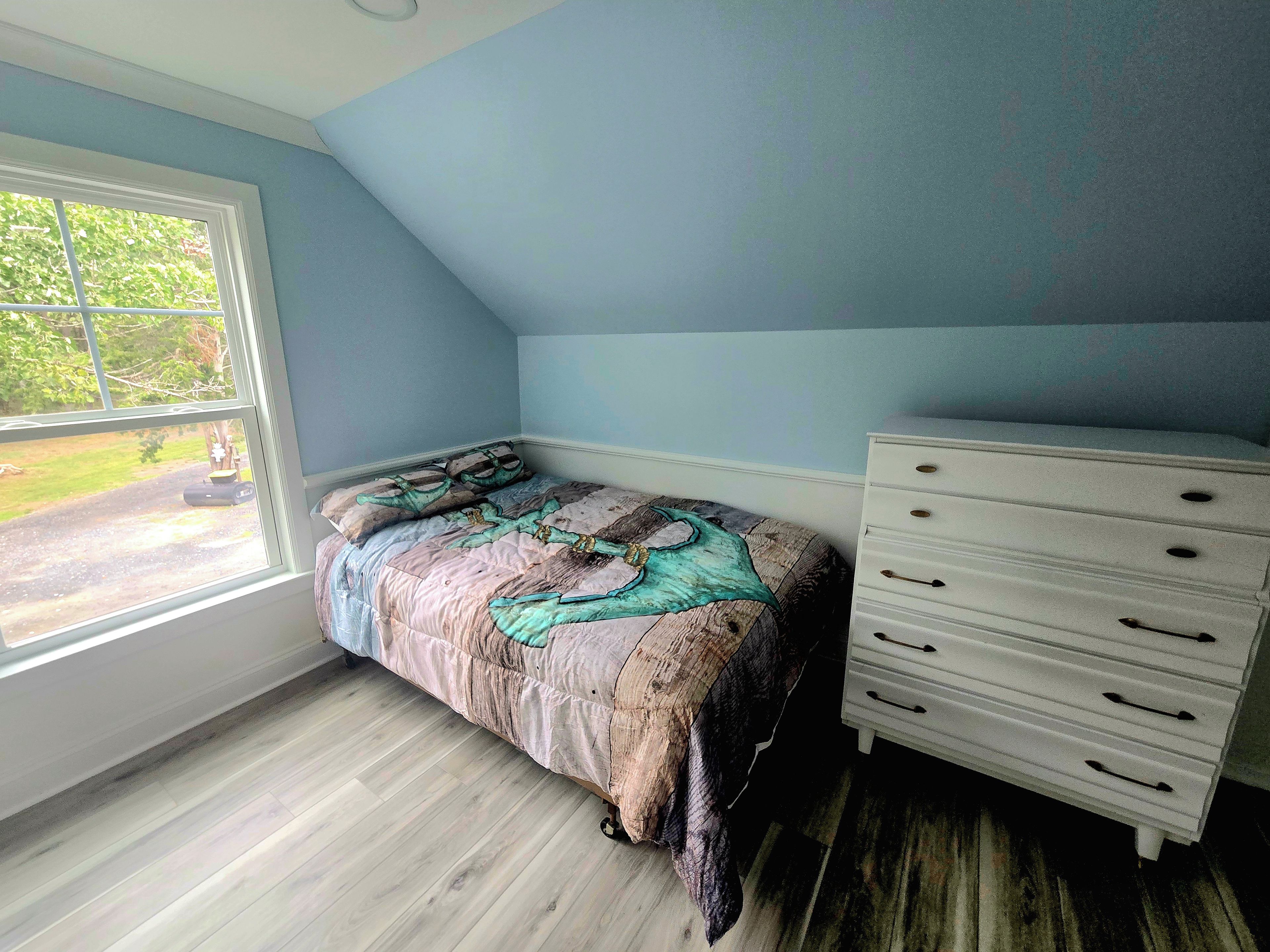 Un dormitorio con cama, cómoda y ventana.