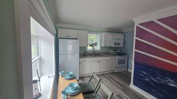 A kitchen with white cabinets, a refrigerator, a microwave, and a stove.
