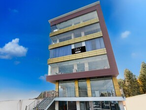 A multi-story building with a glass facade, a visible company sign, and a staircase leading to the entrance.
