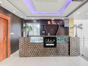 A reception desk with a patterned design, a sign indicating it's company-serviced, and a view of the outside through a window.
