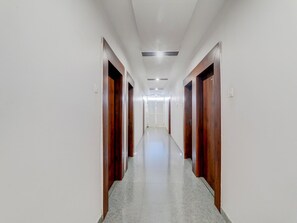 Um corredor comprido e estreito com portas de madeira em ambos os lados e piso de azulejos.