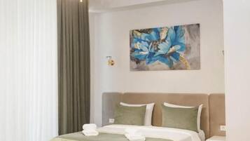 Una habitación de hotel con una cama, una araña, un cuadro y una mesita de noche.