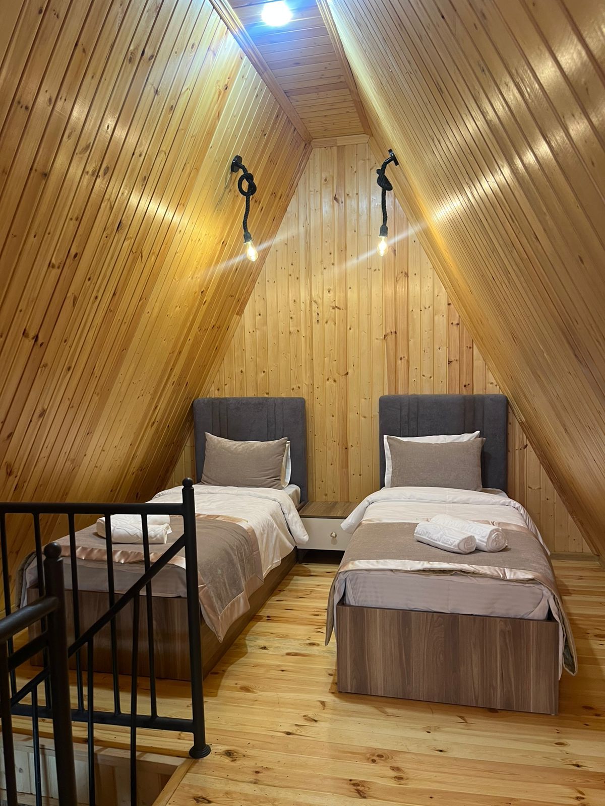Un dormitorio ático acogedor con dos camas, paredes de madera y una escalera.