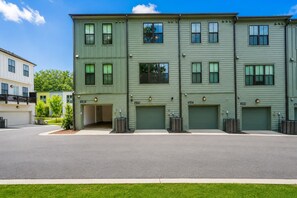 A multi-story residential building with a garage entrance and a driveway. - Upscale Townhome 3 Ensuites Near BeltLine (Atlanta)