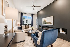A modern living room with a fireplace, a sofa, a blue armchair, and a coffee table. - Upscale Townhome 3 Ensuites Near BeltLine (Atlanta)
