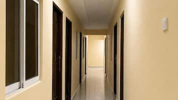A hallway with doors on both sides, a tiled floor, and a light fixture on the ceiling.