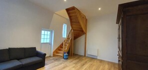 A room with a wooden staircase, a sofa, and a radiator.