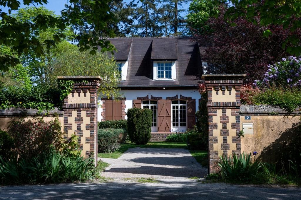 A traditional house with a brick facade, a central door with shutters, and a paved driveway leading to the entrance.