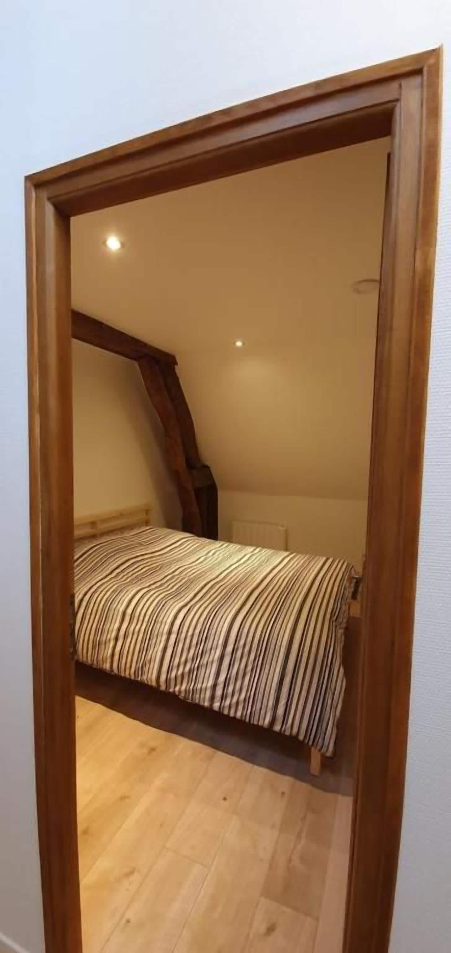 A bedroom with a sloped ceiling, a bed with striped bedding, and a wooden headboard.