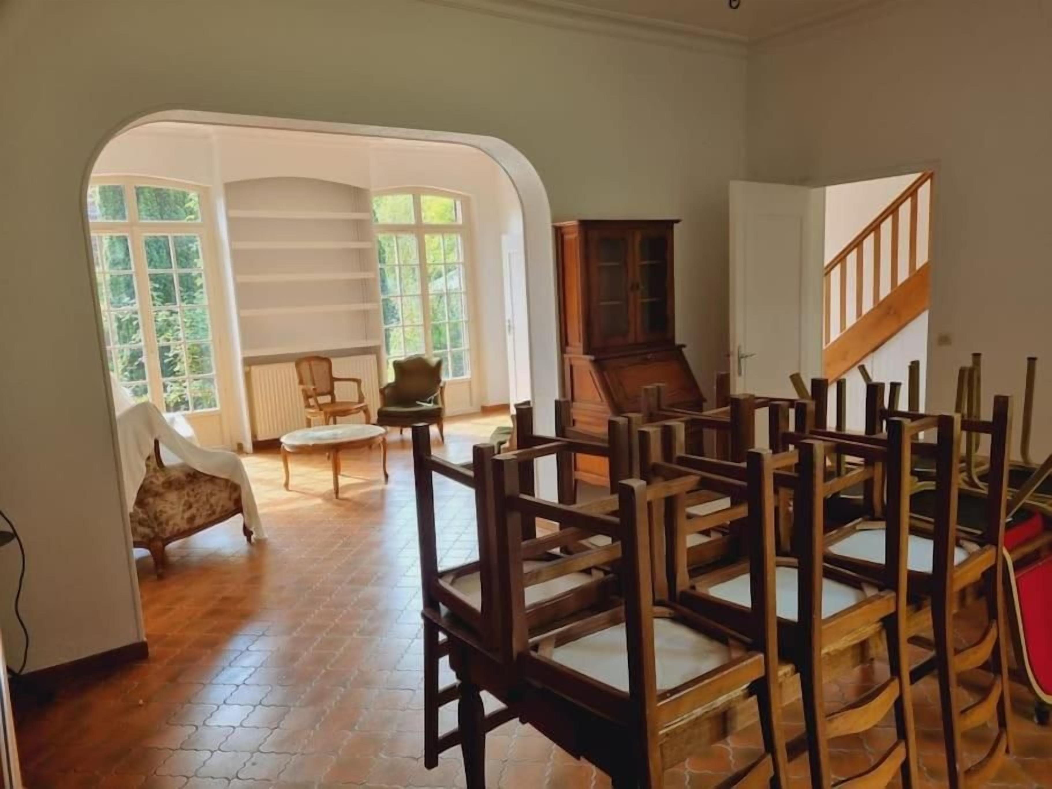 A room with a wooden floor, a chair, a cabinet, and a staircase.