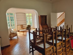 A room with a wooden floor, a chair, a cabinet, and a staircase.