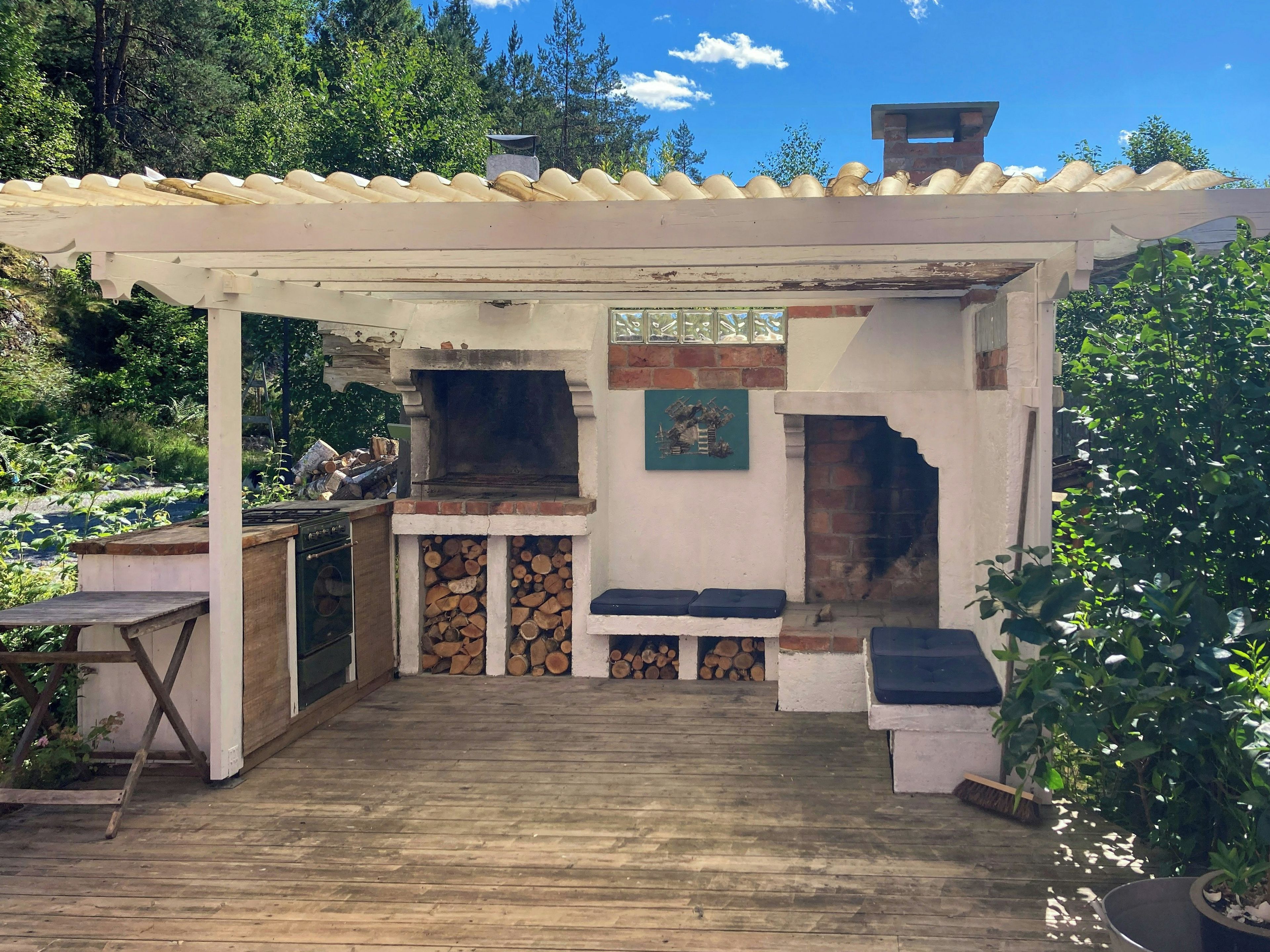 An outdoor patio with a grill, seating, and a chimney.