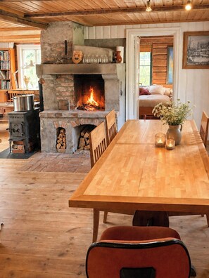Una habitación acogedora con chimenea de piedra, una mesa de comedor y una cama.