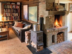 Una sala de estar acogedora con chimenea, un sofá de cuero, una estantería y un horno de ladrillo rústico.