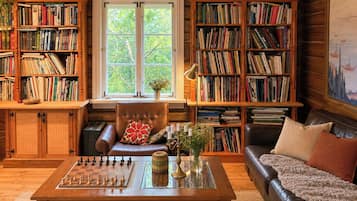 A cozy room with a chessboard, leather furniture, and bookshelves filled with books.