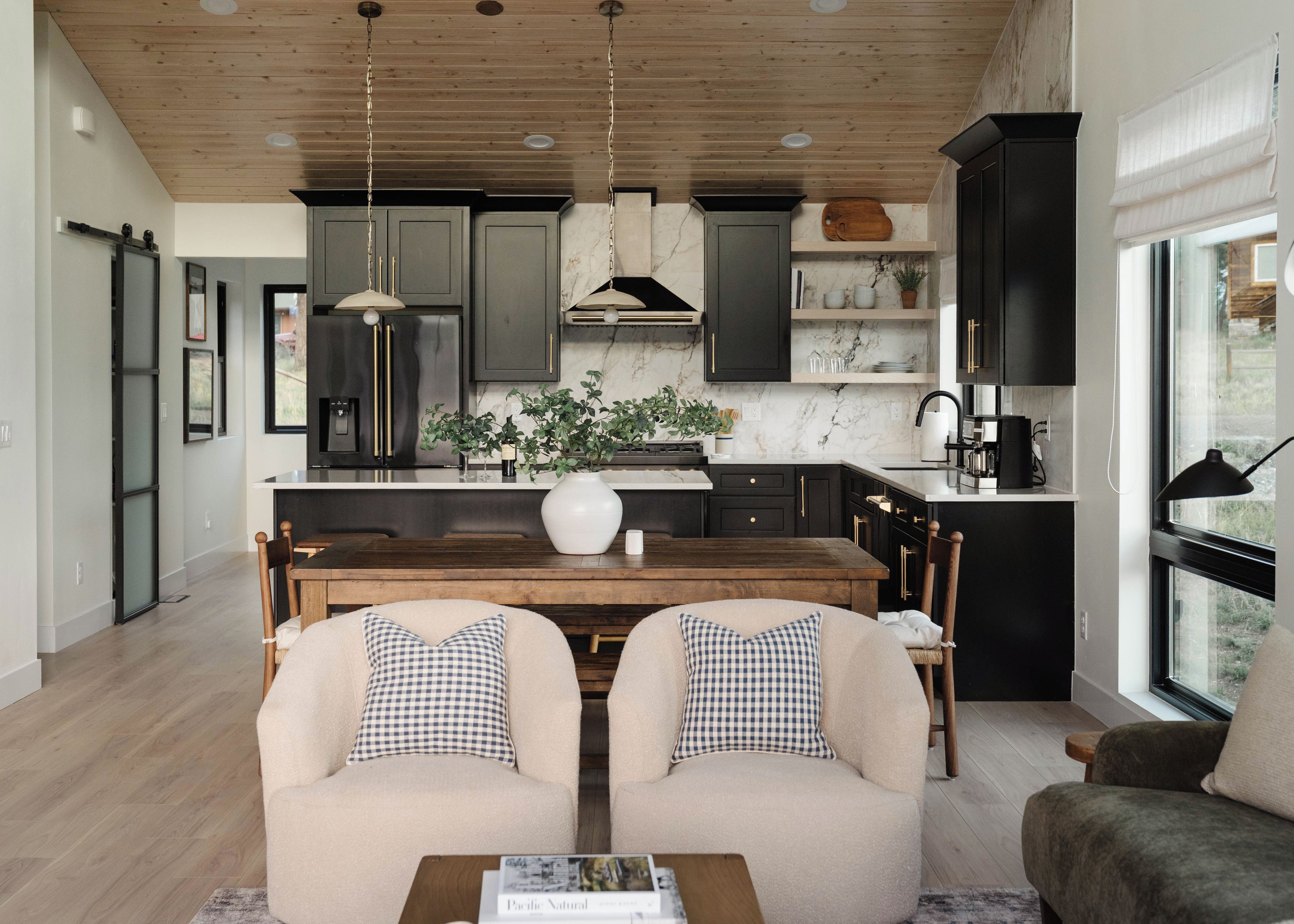Une cuisine moderne avec des meubles de couleur sombre, des plans de travail en marbre et des luminaires suspendus.