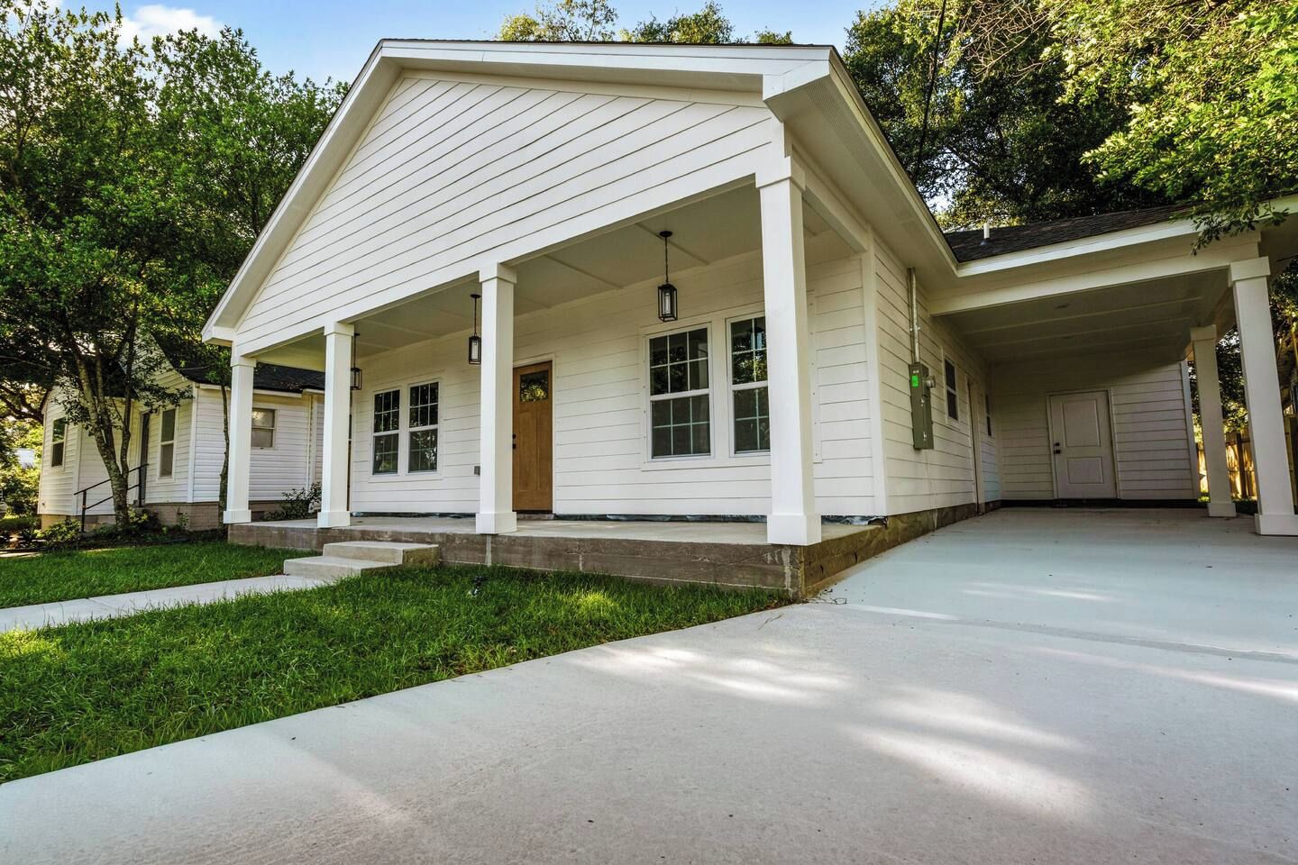 A two-story house with a covered porch, a garage, and a well-maintained lawn.